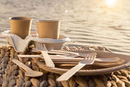 disposable paper cups and utensils on the beach. eco-friendly picnic in nature