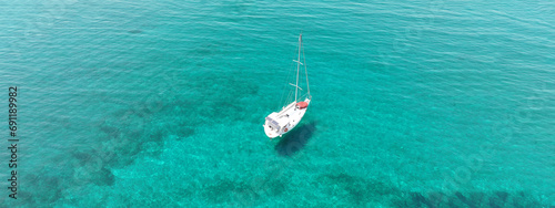 Aerial drone ultra wide panoramic photo of beautiful sail boat with white sails anchored in tropical exotic bay with emerald clear sea © aerial-drone