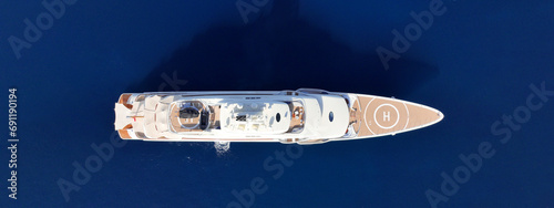 Aerial drone ultra wide top down panoramic photo with copy space of luxury yacht with wooden deck anchored in deep blue island bay with crystal clear sea