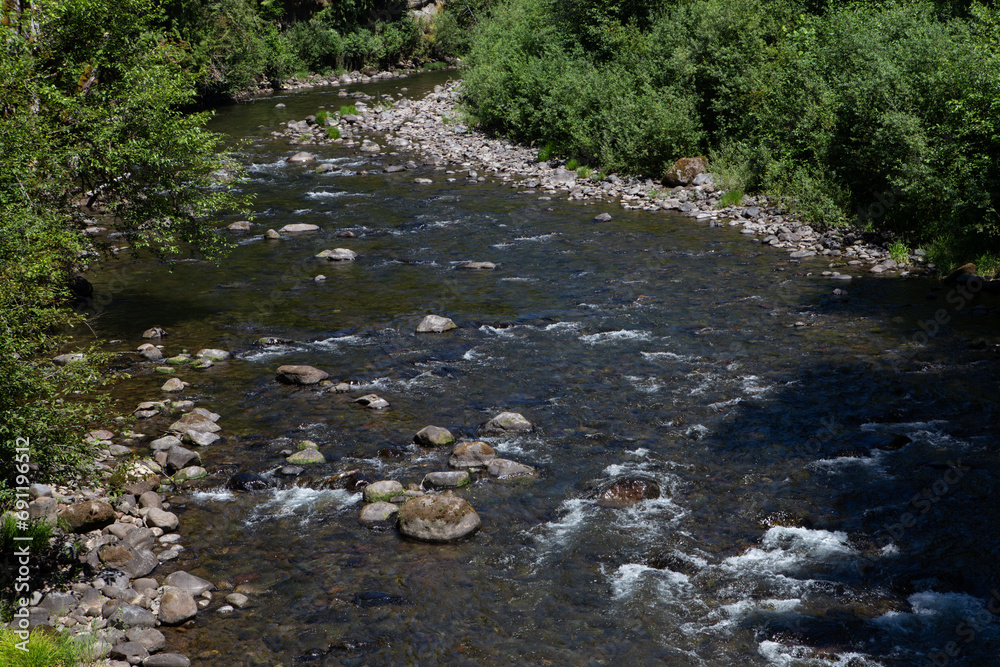 Boulder strewn river in Mount Hood Wilderness near Government Camp, Oregon on a warm summer day with green trees and rushing river Boulder strewn river in Mount Hood Wilderness near Government Camp, Oregon on a warm summer day with green trees and rushing river