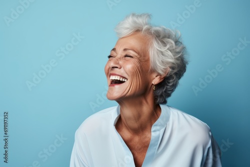 Portrait of happy senior woman laughing and looking at camera against blue background