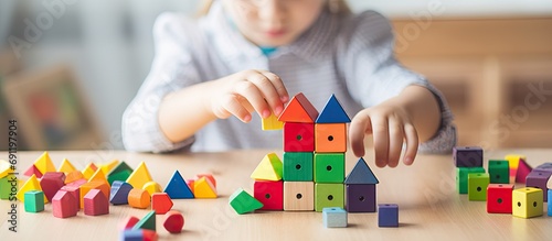 Childish male hands assembling trinomial cube wooden Montessori material on desk closeup top view Alternative education logical ecology construction for learning math algebra geometry arithmeti
