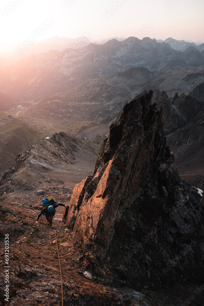 Mountaineer climbs among sharp rocks illuminated by the sunrise in an alpine adventure in the Pyrenees