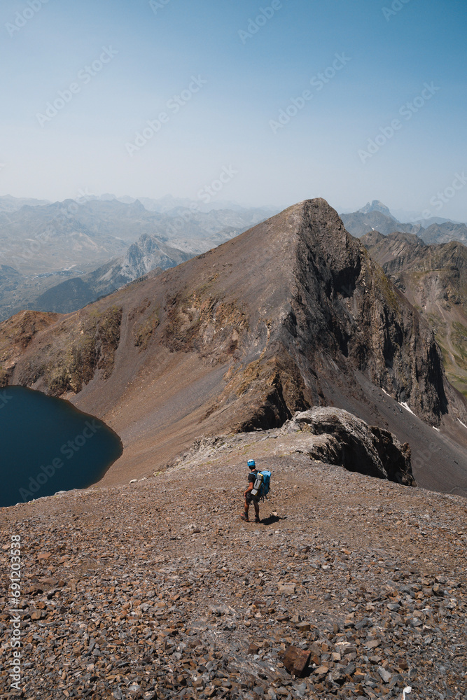 Vertical shot of a mountaineer descending towards the Ibón and Pico de Tebarray in the Pyrenees of Huesca during summer