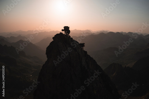 Epic scene with the silhouette of two mountaineers climbing a pinnacle in the Pyrenees backlit during sunrise, with copy space