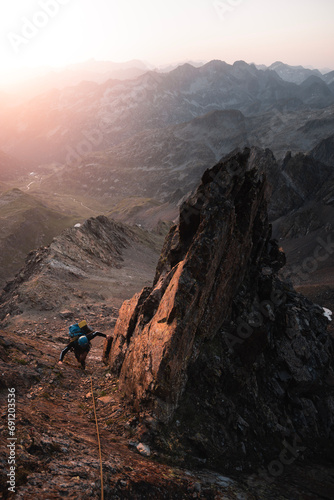 Mountaineer climbs among sharp rocks illuminated by the sunrise in an alpine adventure in the Pyrenees © Larraend Fotografía