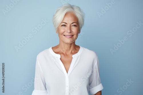 Portrait of beautiful senior woman smiling at camera while standing against blue background
