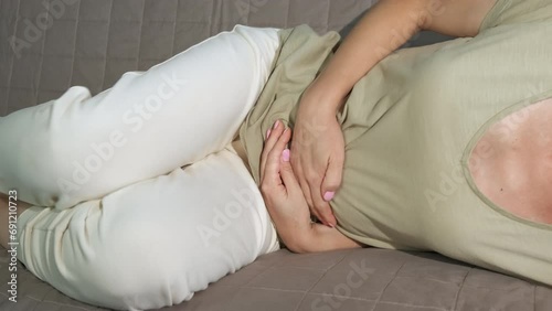 Pregnant woman feeling panic contractions. A pregnant female feeling painful stomach contractions on the sofa. photo