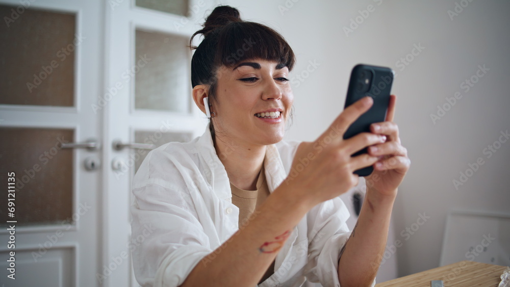 Smiling artist holding smartphone home close up. Earphones woman listening music Smiling artist holding smartphone home close up. Earphones woman listening music