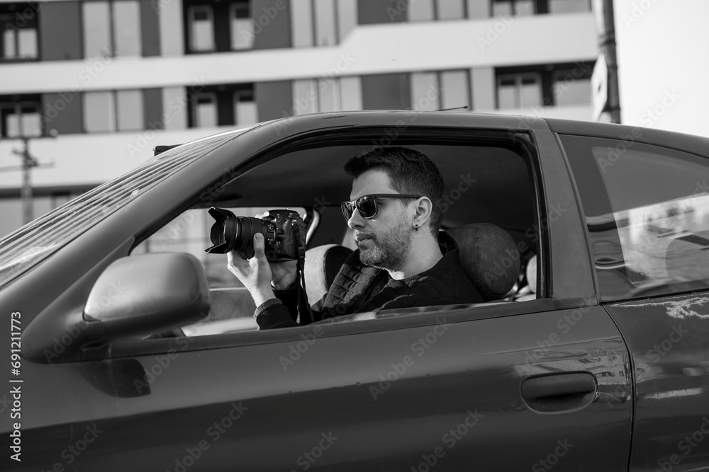 Naklejka premium Black and white image of undercover agent taking pictures from the car 