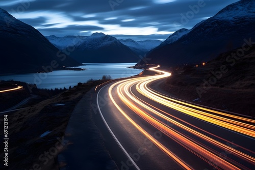 a highway road with cars moving fast with motion blur between snowy mountains photo