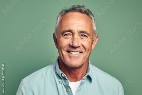 Portrait of happy senior man looking at camera while standing against green background