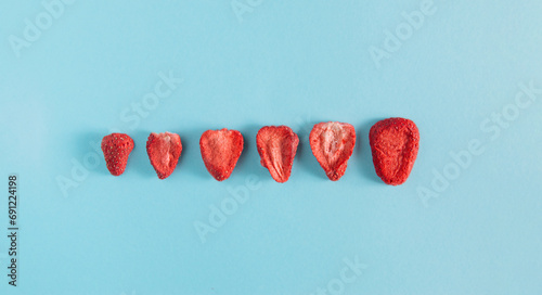 Dehydrated sliced strawberries on the pastel sky-blue background. Dried fruit slices. Freeze healthy chips on a flat lay photography