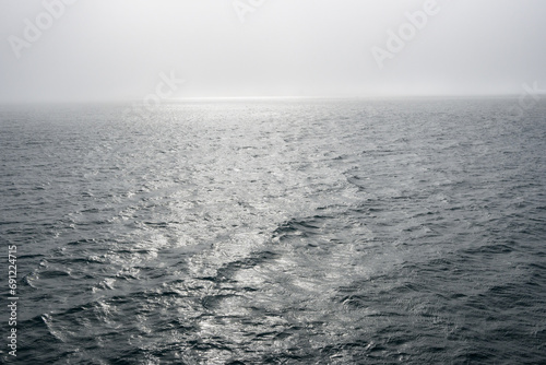 Peaceful early morning fog over the arctic ocean, water to the foggy horizon, as a nature background 