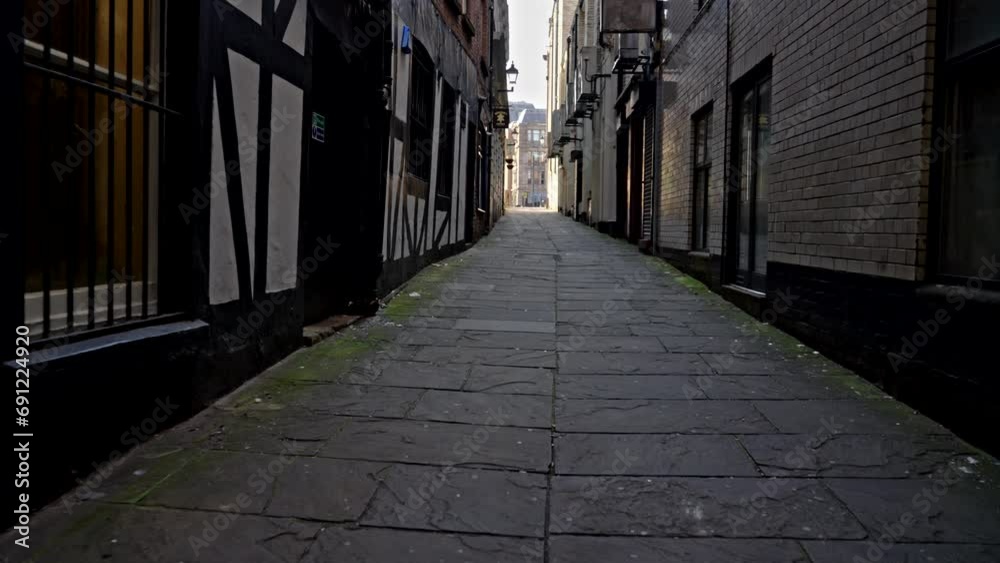 Liverpool, UK - May 20 2023: POV handheld walking down a dark, shadowy stone alleyway toward the bright opening ahead Liverpool, UK - May 20 2023: POV handheld walking down a dark, shadowy stone alleyway toward the bright opening ahead