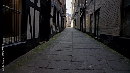 Liverpool, UK - May 20 2023: POV handheld walking down a dark, shadowy stone alleyway toward the bright opening ahead photo