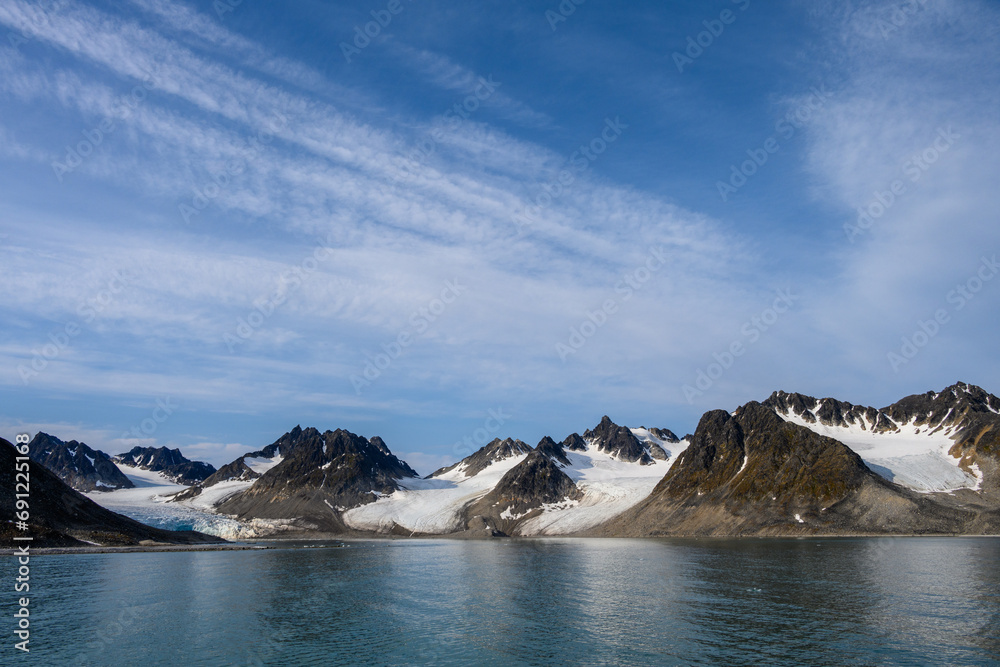 Dramatic clouds in the sky above the mountain peaks in Magdalena Fjord, Svalbard, in the summer arctic

