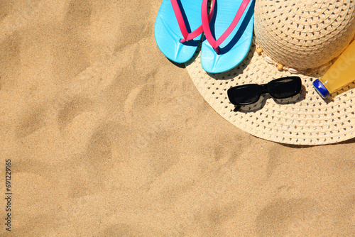 Straw hat, sunglasses, flip flops and refreshing drink on sand, flat lay with space for text. Beach accessories photo