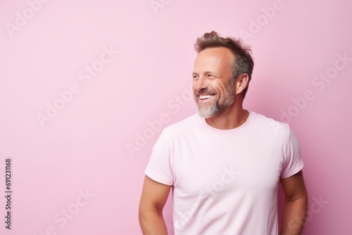 Portrait of a happy mature man smiling and looking at camera against pink background