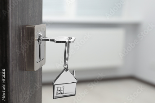 Mortgage and real estate. Open door with key and house shaped keychain against blurred background, space for text