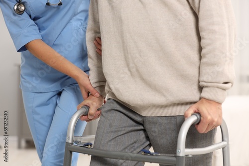 Nurse helping elderly patient with walker indoors, closeup