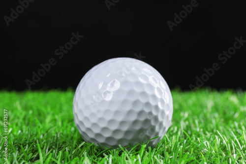 Golf ball on green grass against black background  closeup