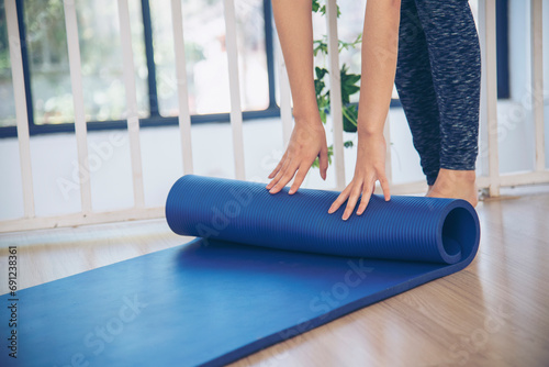 Home workout woman close up hands rolling foam yoga gym mat. Woman hands rolled up yoga mat on gym floor in yoga fitness training room. Woman barefoot home workout sportive healthy lifestyle concept