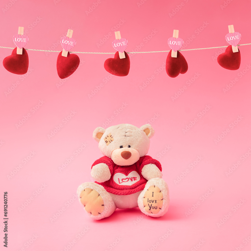 Love composition made of teddy bear and holding a heart-shaped on pastel pink background. Minimal concept of Valentine's Day or love. Creative art, minimal aesthetics.
