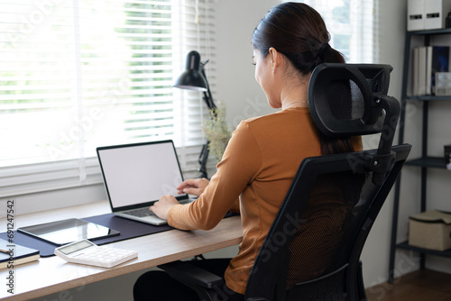 Young Asia businesswoman use laptop with blank white screen mock up display for advertising text while working at her workplace
