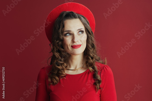 pensive elegant woman in red dress and beret isolated on red