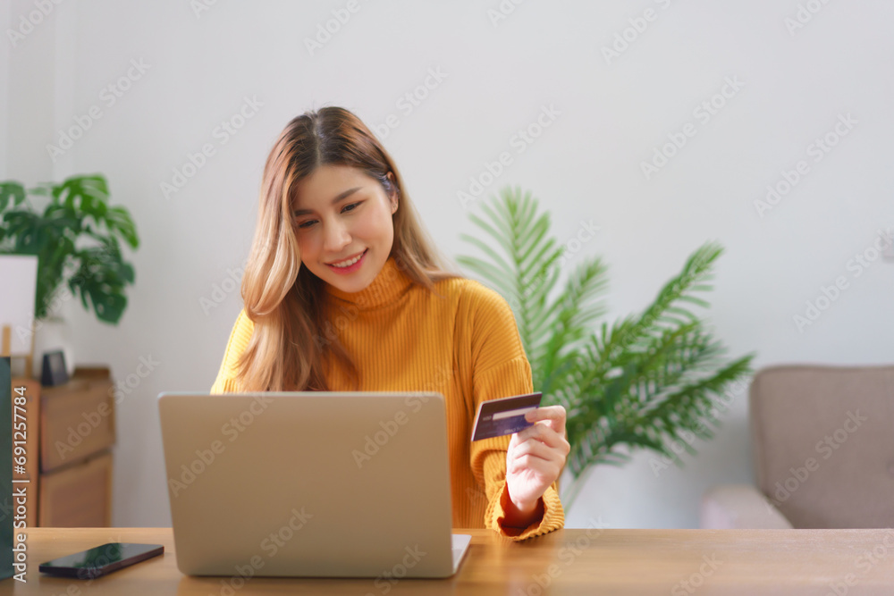Business at home concept, Young Asian woman is typing credit card data on laptop to shopping online Business at home concept, Young Asian woman is typing credit card data on laptop to shopping online