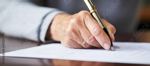 Elderly woman's hand signing document up close.