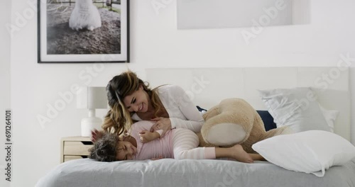 Play, laugh and mom with child on bed for morning love, fun and bonding with teddy bear in home. Smile, tickle and support, mother and daughter in bedroom together with toys, happy woman and kid. photo