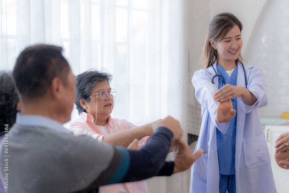 Fototapeta premium Portrait of elderly smiling Asian woman and people aerobics in nursery house. Seniors are moving their body arms and shoulders for a healthy life. retired people activities group concept.