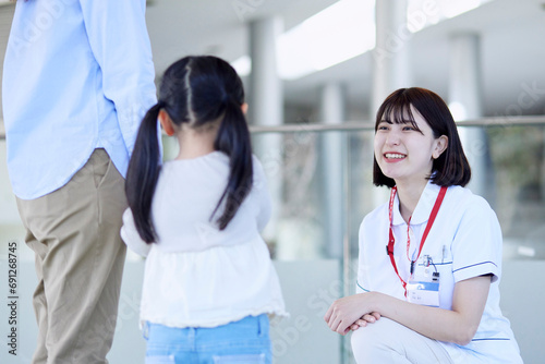 病院内にて話す笑顔の看護師と患者の子供 photo