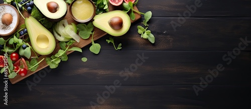 Wooden table with avocado, arugula, kiwi, and gorgonzola in a flat lay.