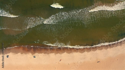 Bird eye view of drone flying above the seashore beach and ocean waves at the sunset photo