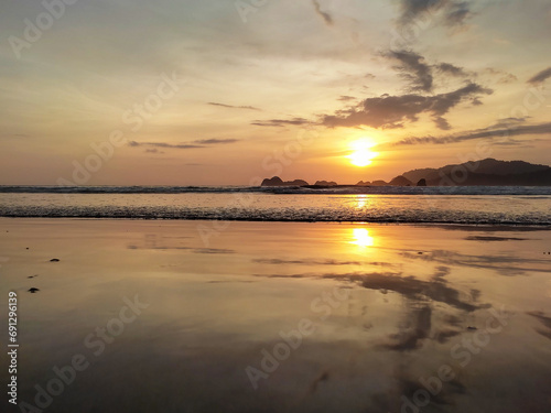 Fototapeta Naklejka Na Ścianę i Meble -  The evening atmosphere at Pulau Merah Beach, Banyuwangi Regency, showing the sun setting in the Indian Ocean.