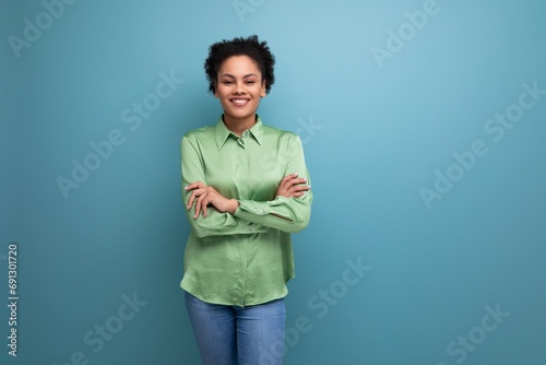 Canvas Print young pretty latin business lady in green shirt posing on blue background with c