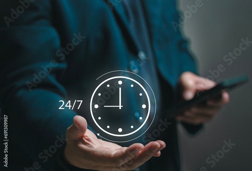 Concept of 24x7 hour MA. Businessman holding a watch icon in his hand. standard service, non-stop and full Maintenance. Business contact center helpdesk for assistant help. onsite service. photo