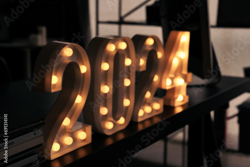 2024 sign lit up in the dark room.
