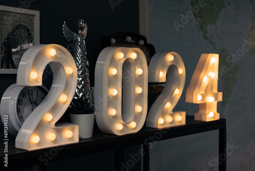2024 sign lit up in the dark room.

