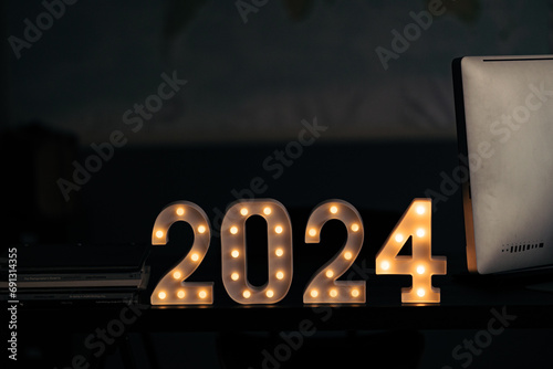 2024 sign lit up in the dark room.
