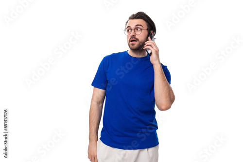 young brunette european man with a beard in a blue t-shirt looks away on a white background with copy space © Ivan Traimak