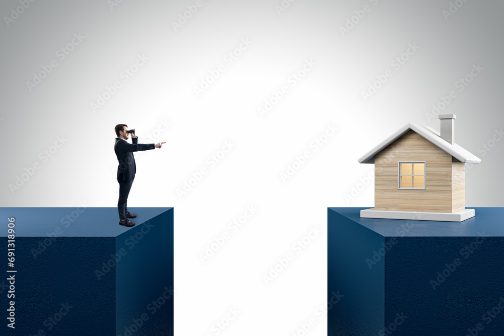Businessman with telescope pointing at wooden house divided by gap on light background. Mortgage and loan concept. - obrazy, fototapety, plakaty 