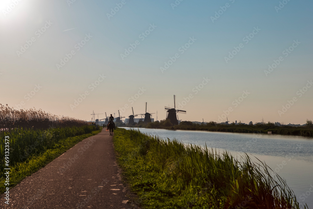 Traditional Romantic Dutch Windmills in Kinderdijk Village in the Netherlands With Water Canal and Horse Riding Tours.