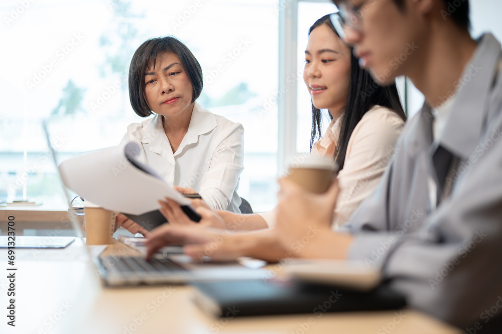 A professional and experienced senior Asian female boss is in the meeting with her team. A professional and experienced senior Asian female boss is in the meeting with her team.