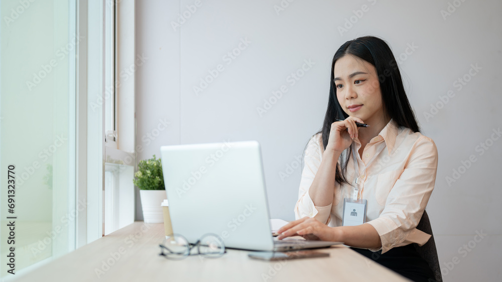 A focused and professional Asian businesswoman is working on her laptop computer in the office. A focused and professional Asian businesswoman is working on her laptop computer in the office.