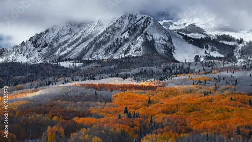 Dramatic Kebler Pass Crested Butte Colorado stunning fall winter first snow seasons collide aerial cinematic drone yellow aspen tree forest Rocky Mountains fog clouds lifting circle right motion photo