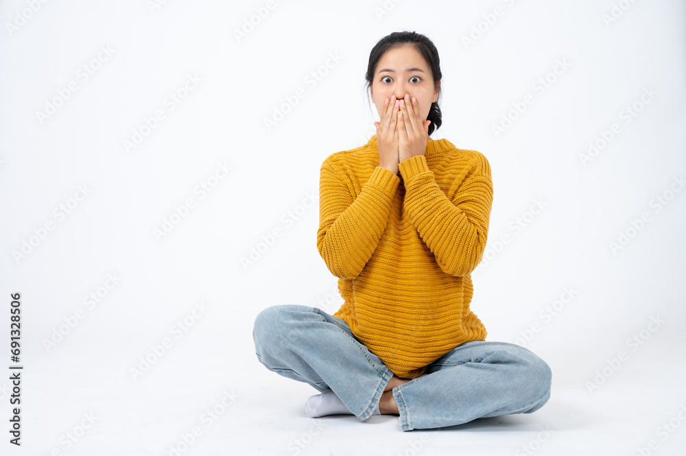 An amazed and stunned young Asian woman is covering her mouth, feeling shocked and surprised. An amazed and stunned young Asian woman is covering her mouth, feeling shocked and surprised.
